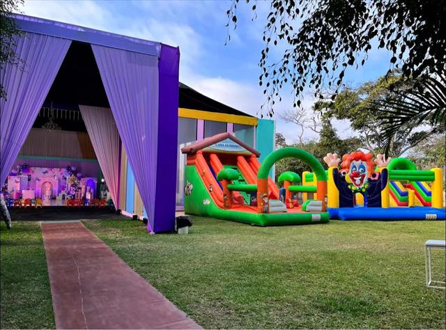 Evento con inflables armados al aire libre y una carpa de cortinas moradas