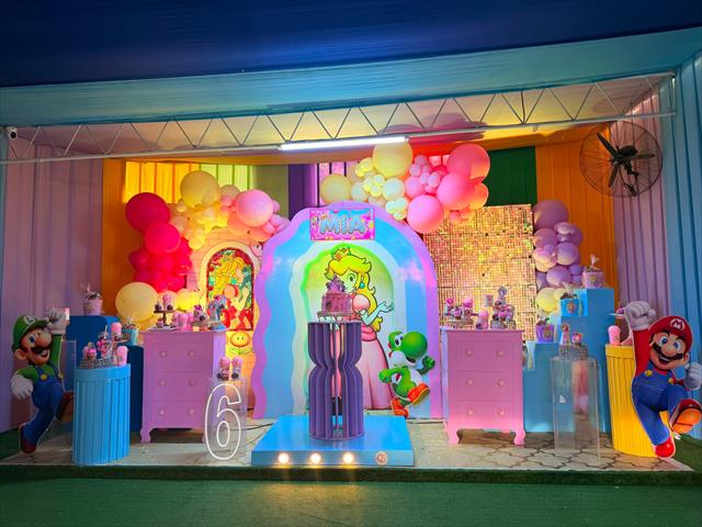 Escenario de cumpleaños con globos de colores y mesas de dulces