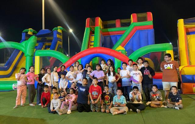 Grupo grande de niños posando juntos frente a los inflables, de noche